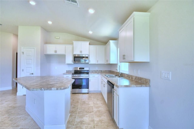 kitchen featuring stainless steel appliances, lofted ceiling, a kitchen island, white cabinets, and sink