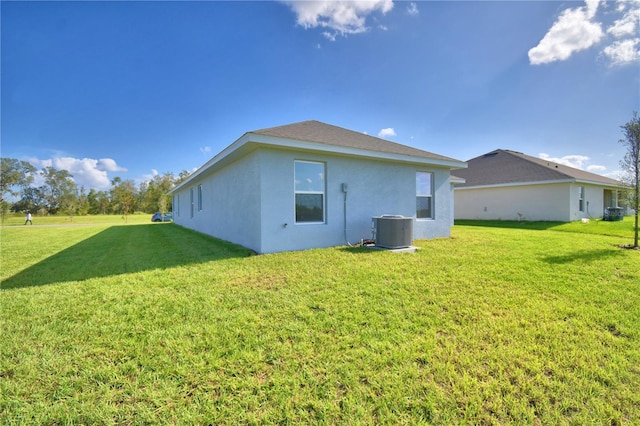 back of house with central AC unit and a yard