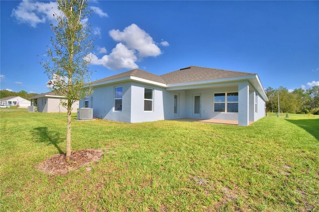 rear view of house featuring central AC and a lawn