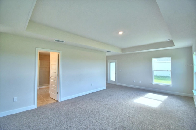 carpeted spare room featuring a tray ceiling