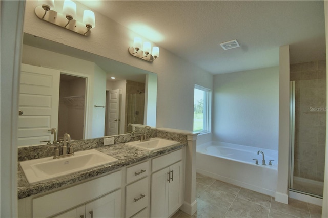 bathroom featuring a textured ceiling, independent shower and bath, tile patterned floors, and vanity