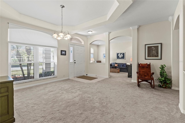 carpeted entrance foyer with a tray ceiling and a notable chandelier