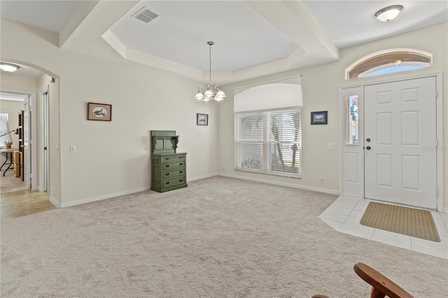 foyer featuring a chandelier, a raised ceiling, and light carpet