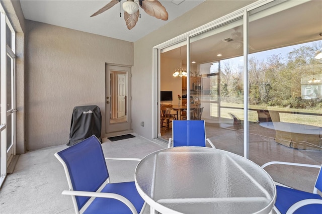 sunroom with ceiling fan with notable chandelier