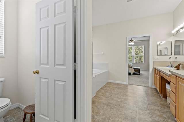 bathroom with vanity, a tub to relax in, ceiling fan, and toilet