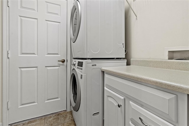 laundry area featuring cabinets and stacked washer and clothes dryer