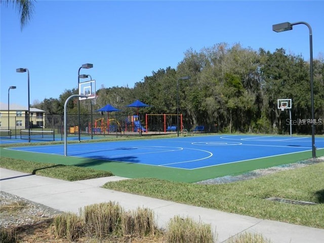 view of sport court featuring tennis court and a playground