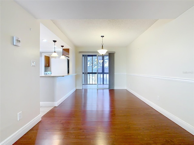 unfurnished dining area featuring dark wood-type flooring and a textured ceiling