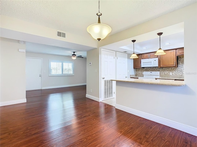 kitchen with backsplash, white appliances, dark wood-type flooring, pendant lighting, and light stone counters