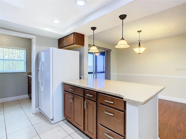 kitchen featuring light tile patterned floors, white fridge with ice dispenser, light stone countertops, a textured ceiling, and pendant lighting