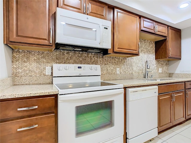 kitchen featuring light tile patterned floors, backsplash, white appliances, light stone countertops, and sink