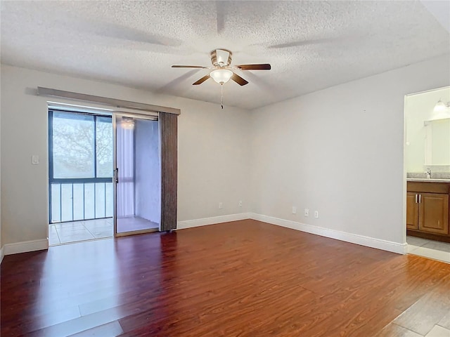 empty room featuring ceiling fan, sink, a textured ceiling, and hardwood / wood-style floors