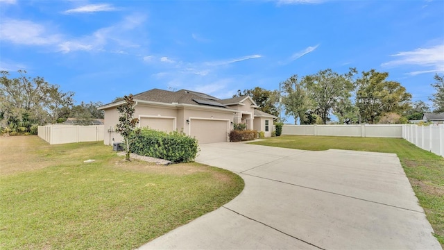 view of front of property featuring a garage, solar panels, and a front yard