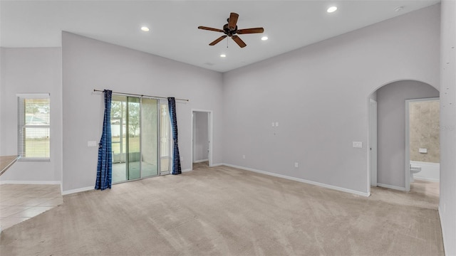 empty room featuring ceiling fan, light colored carpet, and a high ceiling