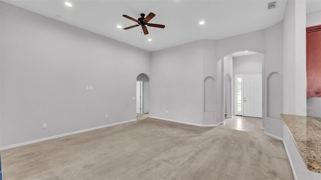 carpeted empty room with ceiling fan and a high ceiling