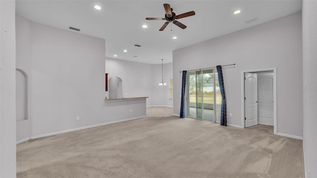 carpeted spare room featuring ceiling fan with notable chandelier