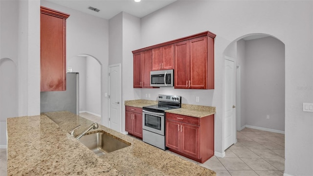 kitchen featuring light stone countertops, light tile patterned floors, appliances with stainless steel finishes, and sink