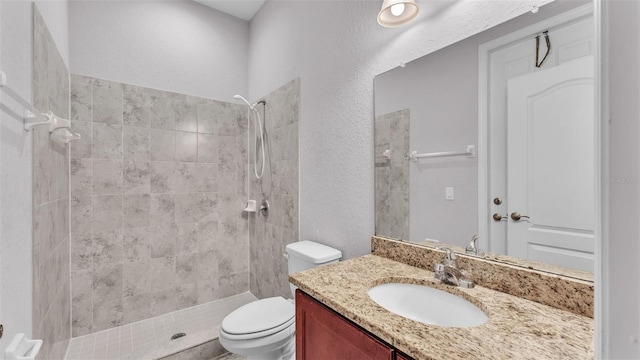 bathroom featuring toilet, vanity, and tiled shower