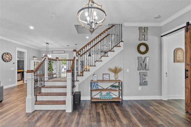 staircase with a barn door, a notable chandelier, crown molding, and hardwood / wood-style floors