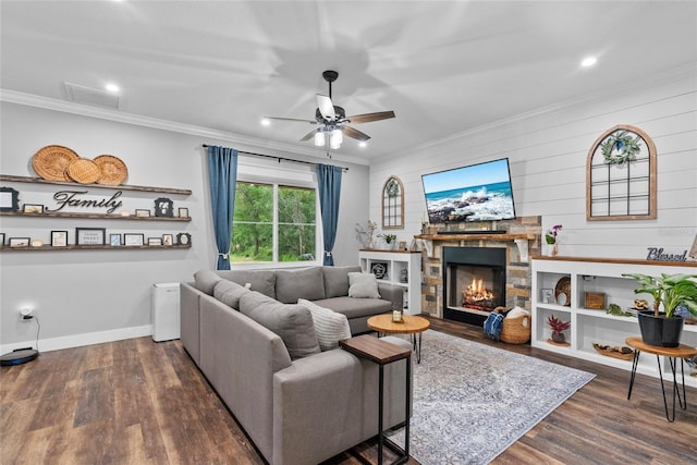 living room featuring dark wood-type flooring, crown molding, a stone fireplace, and ceiling fan