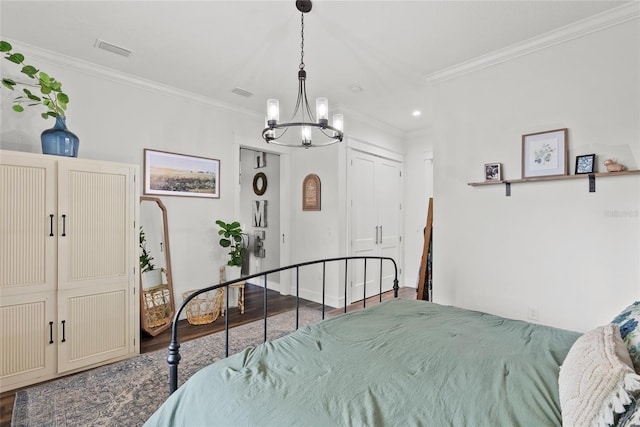 bedroom featuring hardwood / wood-style flooring, crown molding, and an inviting chandelier