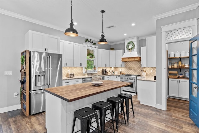 kitchen featuring white cabinetry, a kitchen bar, high end appliances, and a kitchen island