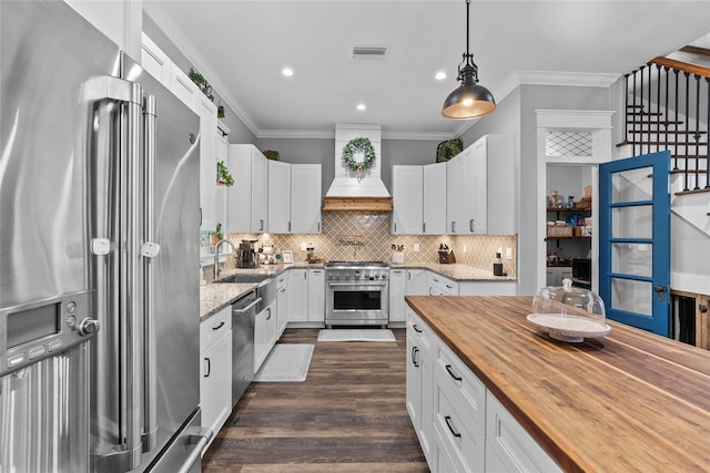 kitchen featuring white cabinetry, custom exhaust hood, wooden counters, hanging light fixtures, and high quality appliances