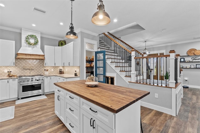 kitchen with decorative light fixtures, stainless steel range, white cabinetry, and a center island