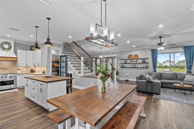 dining space featuring ornamental molding, ceiling fan with notable chandelier, and wood-type flooring