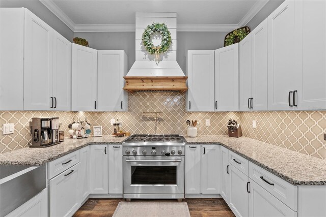 kitchen featuring high end stainless steel range oven, white cabinets, and custom exhaust hood