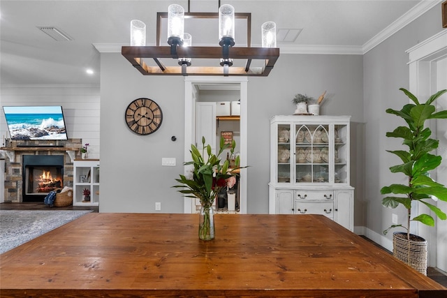 dining space with a fireplace and ornamental molding