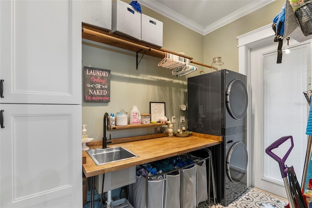 laundry room with stacked washer and dryer, sink, crown molding, and cabinets