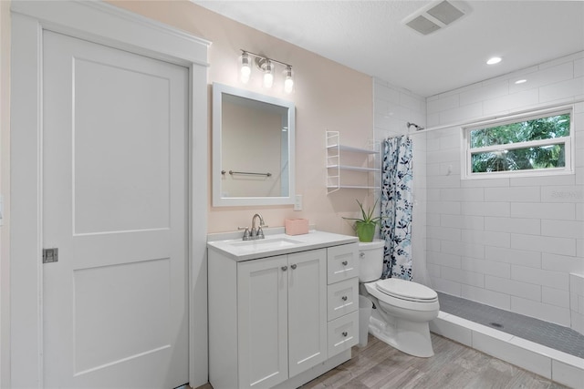 bathroom with curtained shower, wood-type flooring, toilet, and vanity