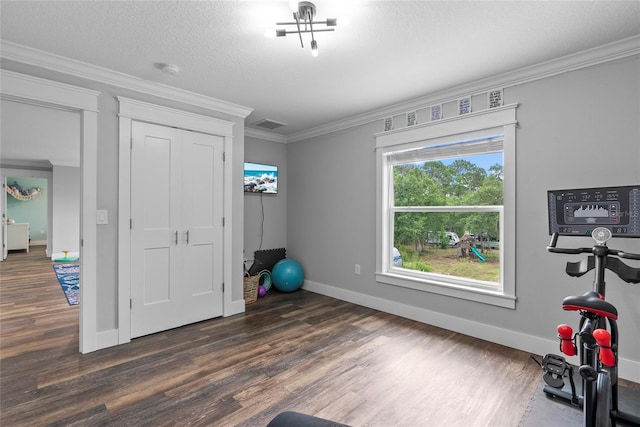 workout room with a textured ceiling, dark hardwood / wood-style flooring, and crown molding