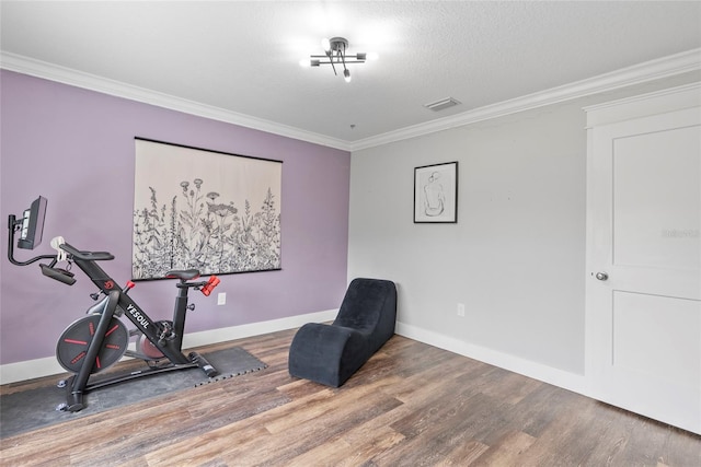 workout room featuring a textured ceiling, crown molding, and wood-type flooring