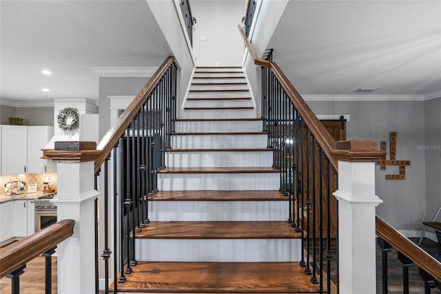 staircase featuring crown molding, a textured ceiling, and hardwood / wood-style flooring