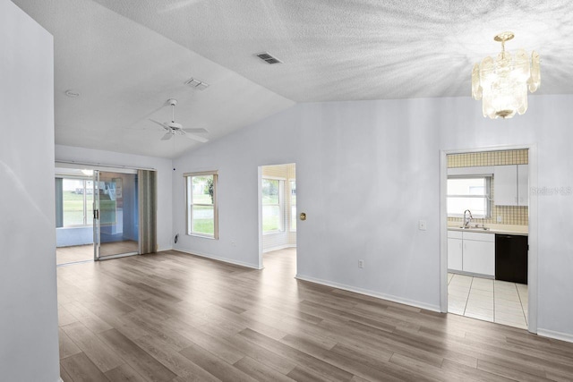 unfurnished room featuring sink, ceiling fan with notable chandelier, vaulted ceiling, and wood-type flooring