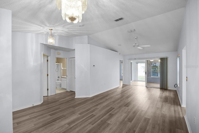 spare room with ceiling fan with notable chandelier, dark wood-type flooring, high vaulted ceiling, and a textured ceiling