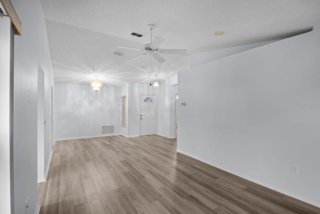 empty room with ceiling fan, lofted ceiling, light hardwood / wood-style floors, and a textured ceiling