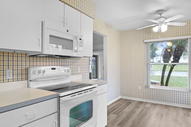 kitchen with white cabinetry, light wood-type flooring, ceiling fan, and white appliances