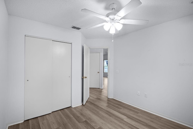 unfurnished bedroom featuring ceiling fan, light hardwood / wood-style flooring, a closet, and a textured ceiling