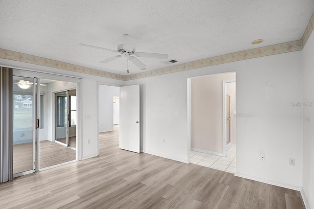 unfurnished room featuring ceiling fan, light wood-type flooring, and a textured ceiling