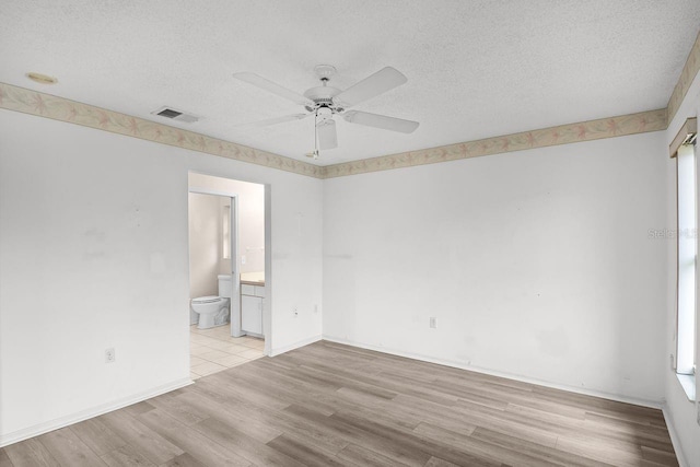 spare room with ceiling fan, light wood-type flooring, and a textured ceiling