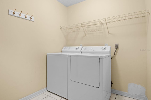 clothes washing area featuring light tile patterned floors and washer and clothes dryer