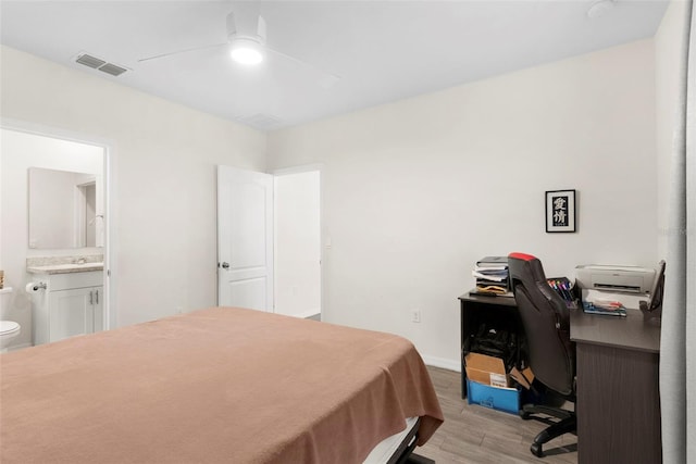 bedroom with light wood-type flooring, sink, ceiling fan, and ensuite bath