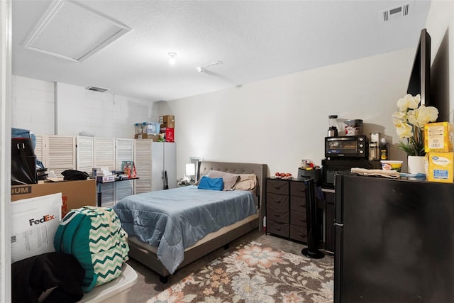 bedroom with a textured ceiling and refrigerator