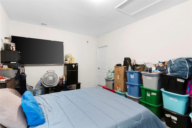 bedroom with black refrigerator and a textured ceiling