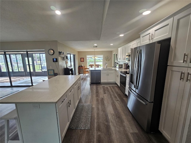 kitchen featuring white cabinetry, stainless steel appliances, kitchen peninsula, and hanging light fixtures