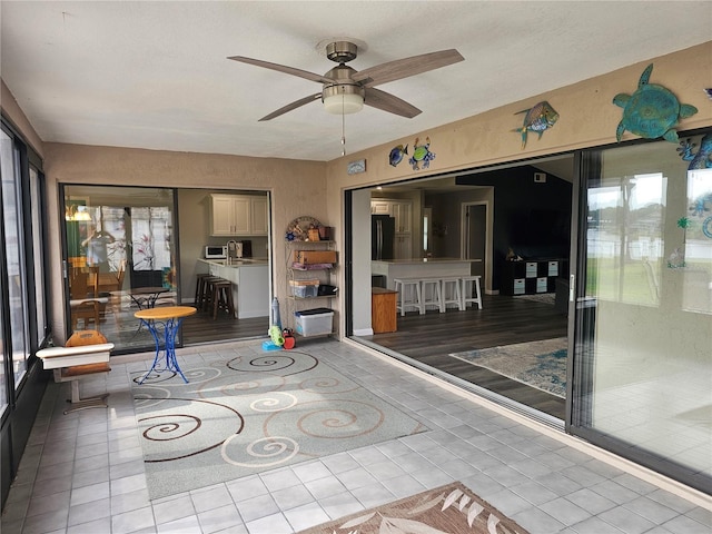 unfurnished sunroom featuring ceiling fan and plenty of natural light