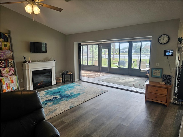 living room with ceiling fan, vaulted ceiling, dark hardwood / wood-style flooring, and a textured ceiling